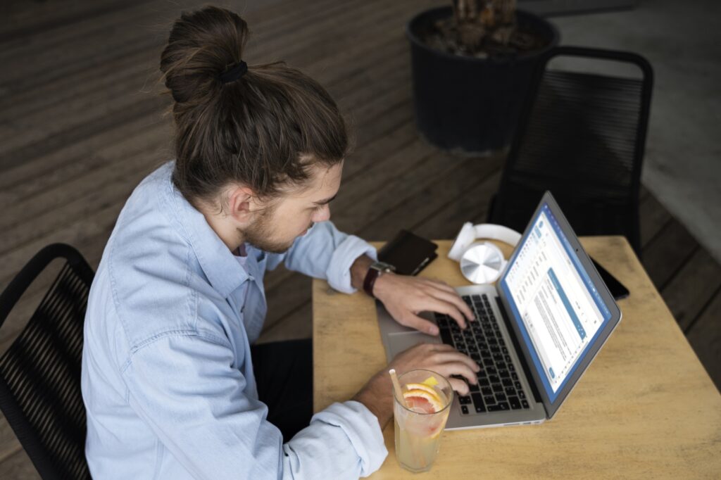 High-angle shot of an employee crafting an email to clients and partners about the office relocation